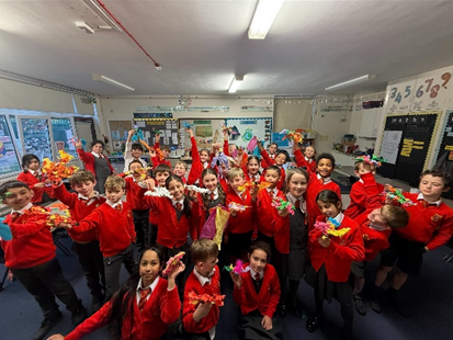 Year 4 class holding up their wire sculpture birds and smiling for a photo.