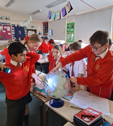 Children rotating a globe in a small group.