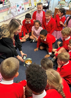 Children gathered around the teacher and a tin pot containing Turkish Delight.