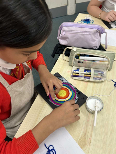 A girl weaves yarn in to a circular shape