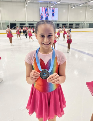 Talia on the ice rink with her medal