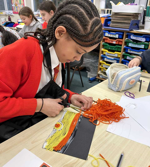 A girl cuts orange yarn 