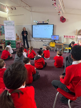 Children sitting around an interactive whiteboard listening to the Anti-bullying workshop leader.
