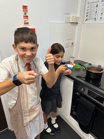 A child giving a thumbs up whilst tasting their sauce.