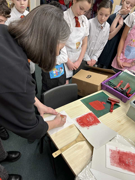 An adult explains the printing process to the children.