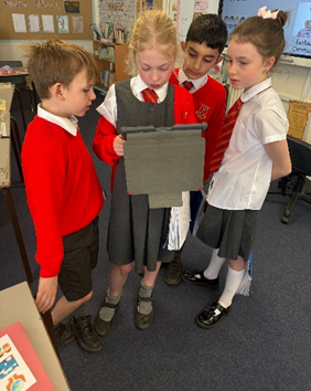 Children gathered around an iPad listening to their podcast ready to make edits. 