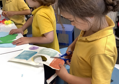 Children cutting out 2D shapes to create their artwork inspired by Henri Matisse.