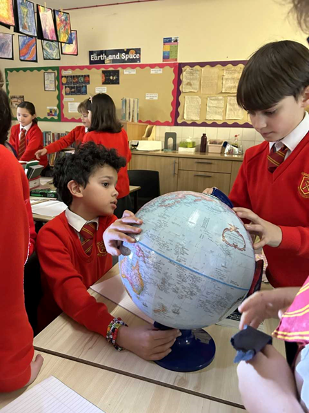 Children rotating a globe in a small group.
