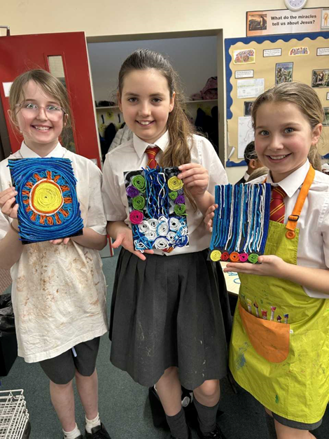 Three children smile and show off their Huichol pieces