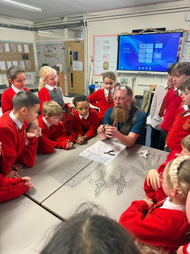 Children gathered around the instructor learning how to mould the wire mesh.