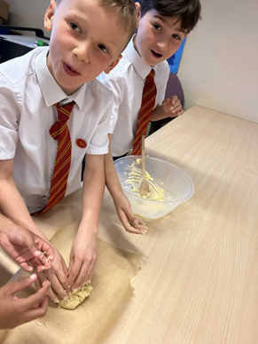 Two children smiling as they form their biscuits