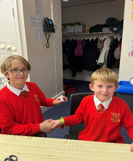 Year 6 child and Year 3 child showing the friendship bracelets they made