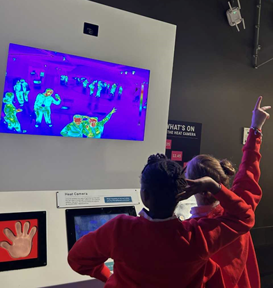 Two children posing at an infrared thermometer