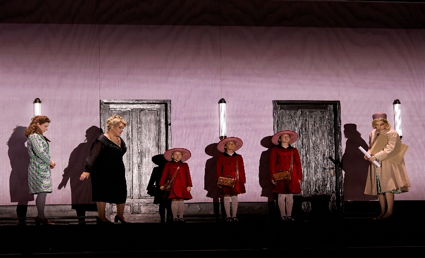photo of 3 girls in red dresses and hats on stage accompanied by 3 women