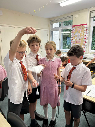Children taking part in an experiment. They holding a mini parachute in the air and letting it fall.