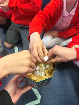 Children’s hands picking out Turkish Delight from the tin. 