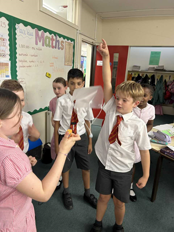 Children taking part in an experiment. They holding a mini parachute in the air and letting it fall.